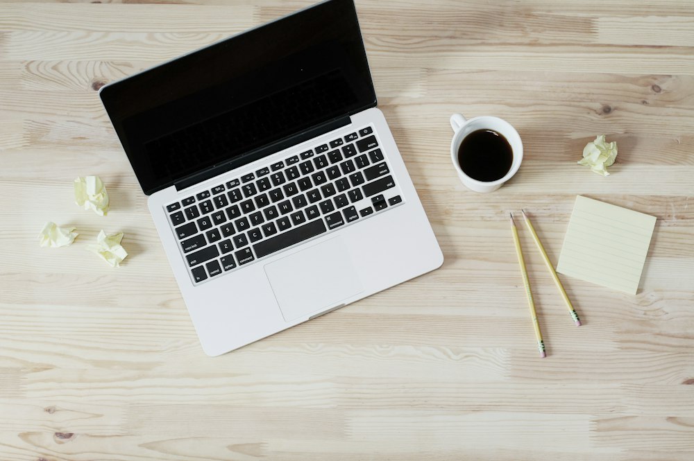 Laptop, kopi, dan buku catatan untuk menyusun checklist landing page
