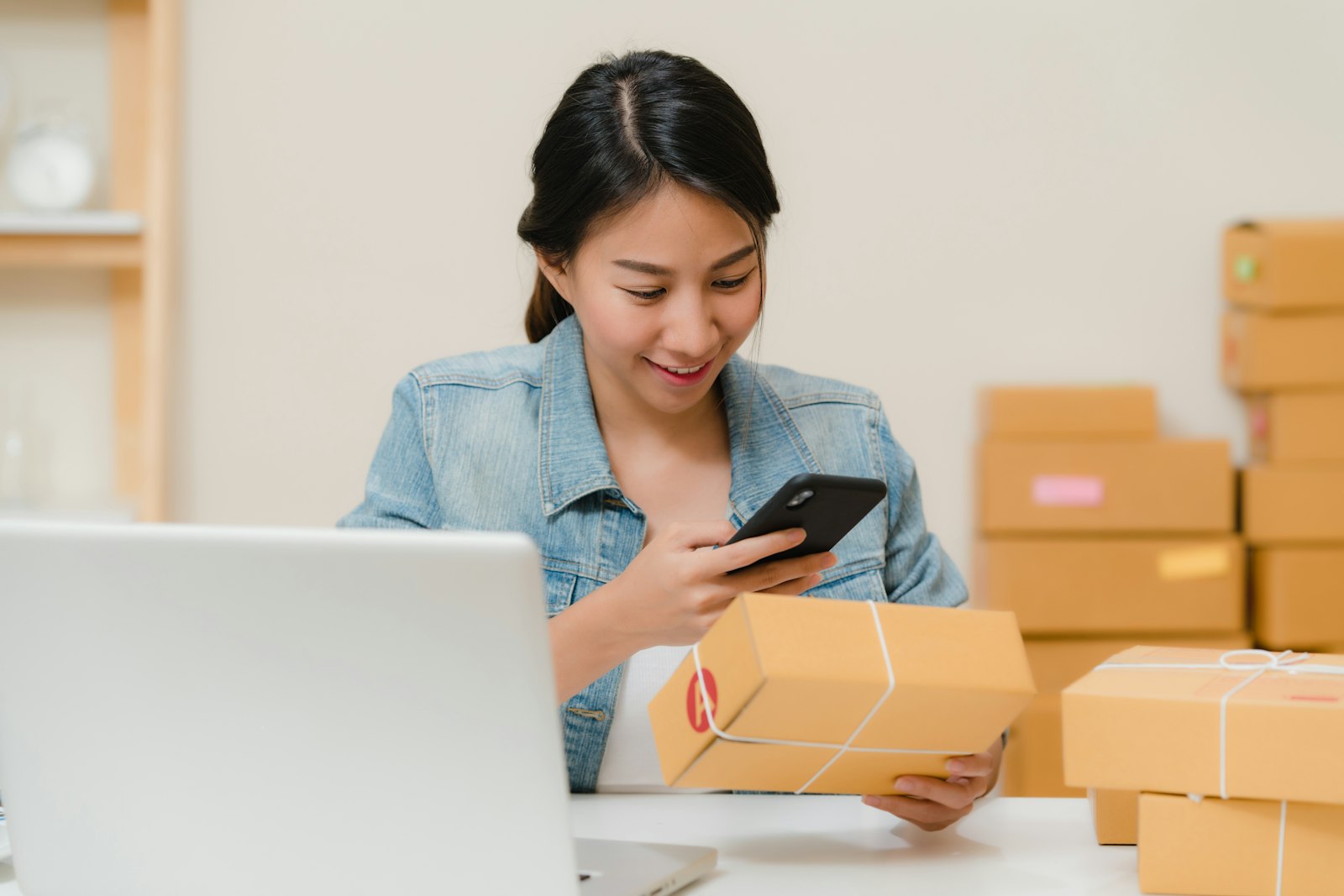 Pelaku UMKM mencatat pesanan pelanggan sambil memeriksa paket yang siap dikirim